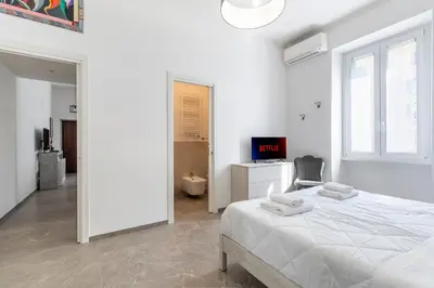 a white bedroom with a bed and a chair at Vatican Essence in Rome