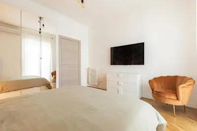a white bedroom with a bed and a chair at A Casa di Nico - Metro B1 Conca d 'Oro in Rome