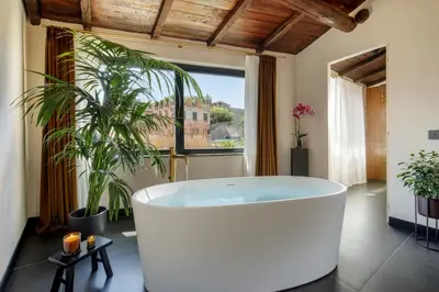 a bath tub in a bathroom with a large window at Daplace - Palazzo Serpe Suites near Colosseum in Rome