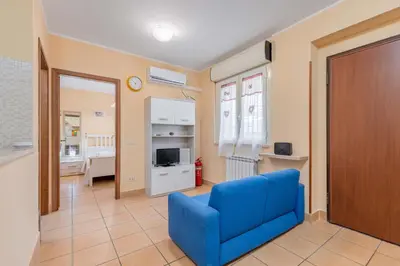 a living room with a blue chair and a television at Casa Roma - La Casetta di Vale in Rome