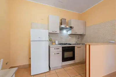 a kitchen with white cabinets and a white refrigerator at Casa Roma - La Casetta di Vale in Rome