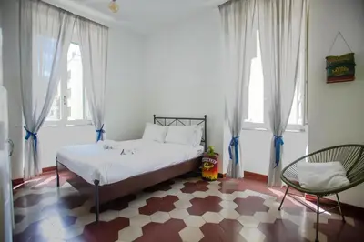 a bedroom with a bed and a chair and windows at Vintage Vibes in Testaccio - Cale 07 in Rome