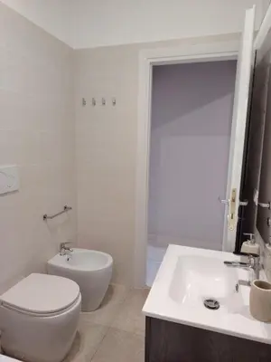 a white bathroom with a toilet and a sink at Sweet Home in Rome