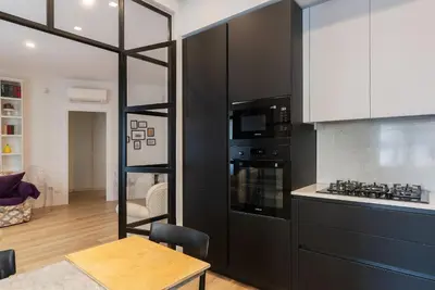 a kitchen with black and white appliances and a table at GuestHost - Charming Apartment Metro Cipro in Rome