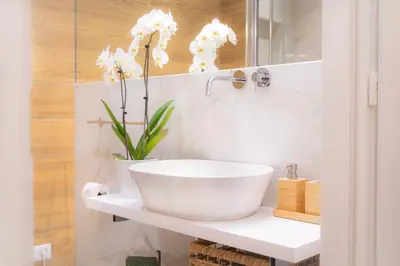 a bathroom with a white sink and flowers on a counter at La Veranda dei Farnesi in Rome