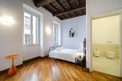 a bedroom with a white bed and a wooden floor at Dadada by BuddyRent in Rome