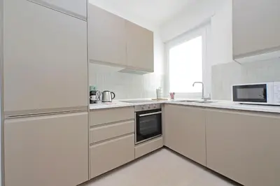 a white kitchen with white appliances and a window at Luminoso appartamento di fronte Metro Piramide in Rome