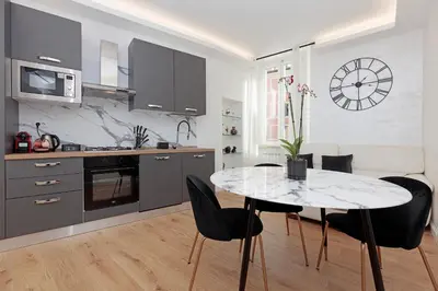 a kitchen with a table and chairs and a clock on the wall at Malva Suite in Rome