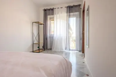 a white bedroom with a bed and a large window at Vacanze Romane in Rome