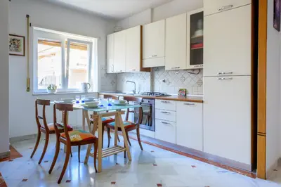 a kitchen with white cabinets and a table and chairs at Vacanze Romane in Rome