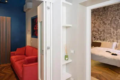 a living room with a red chair and a bed at Dreamers in Belsiana Spagna int 8 in Rome