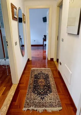 a hallway with a rug on the floor and a mirror at Testaccio 100 in Rome