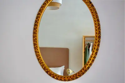 a gold mirror hanging on a wall next to a chair at San Lorenzo Studio Flat in Rome