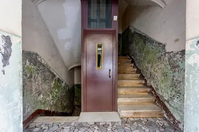 an empty hallway with a brown door and stairs at San Lorenzo Studio Flat in Rome