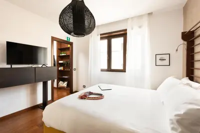 a white bedroom with a bed and a television at Vatican Loft - Mura Vaticane in Rome