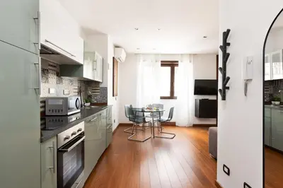a kitchen with white cabinets and a table with chairs at Vatican Loft - Mura Vaticane in Rome