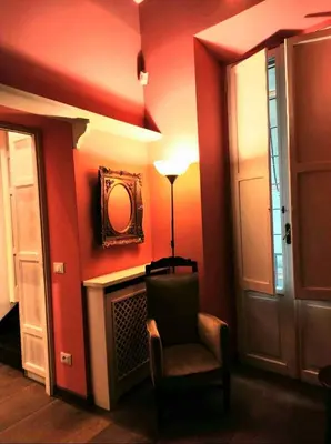 a room with a chair and a mirror on a wall at Library's House in Rome