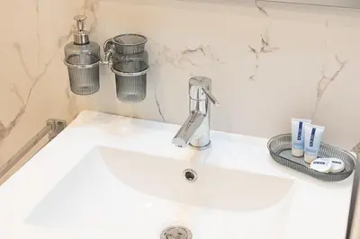 a bathroom sink with a faucet and cups on it at Constance Apartment by Rental in Rome in Rome
