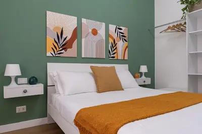 a bedroom with a bed with three paintings on the wall at City Comfort - 20 minutes walk to the Colosseum in Rome