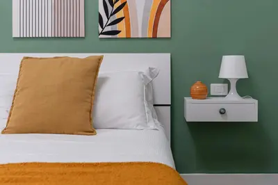 a bed with an orange pillow and a green wall at City Comfort - 20 minutes walk to the Colosseum in Rome