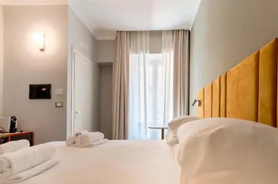 a bedroom with a bed with white sheets and towels at Velia Relais in Rome