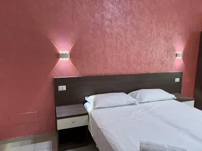 a bedroom with a white bed with pink walls at Tiburtina Hotel Holiday in Rome