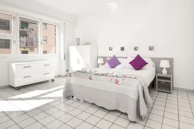 a white bedroom with a large bed with purple pillows at Margaret Guest House in Rome