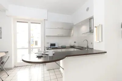 a white kitchen with a table and a sink at Margaret Guest House in Rome