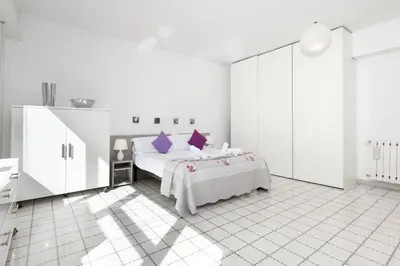 a white bedroom with a bed with purple pillows at Margaret Guest House in Rome