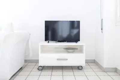 a television on a white tv cart in a room at Margaret Guest House in Rome