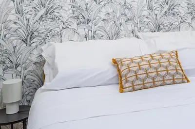 a bed with white sheets and a patterned wall at iFlat Pantheon & La Dolce Vita Skyline Penthouse in Rome