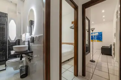 a bathroom with a sink and a mirror and a bedroom at GuestHost - Metro Cipro-Ottaviano Apartment X6 in Rome