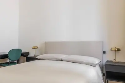 a bedroom with a white bed and a green chair at Suite23 , Roma in Rome