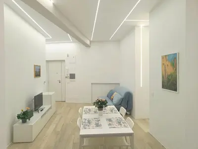 a white living room with a table and a couch at Art & Garden Gemelli - Metro A - Vaticano in Rome