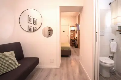 a bathroom with a couch and a toilet and a mirror at Bianca Guest House in Rome