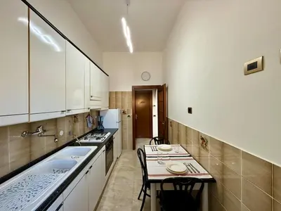 a large kitchen with white cabinets and a table at SanLo Nest in Rome