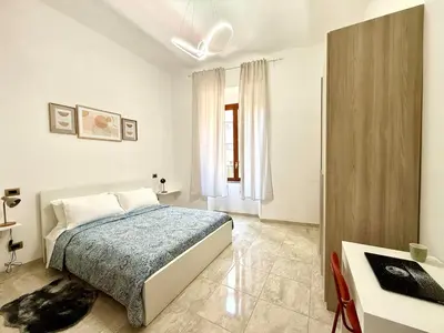 a white bedroom with a bed and a desk at SanLo Nest in Rome