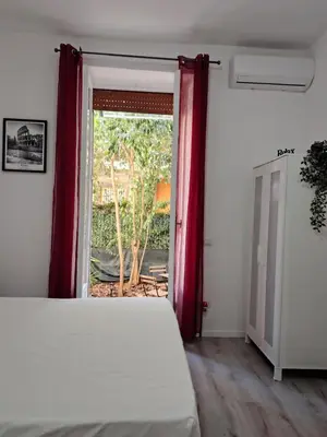 a bedroom with a bed and a window with red curtains at Cozy Home Medaglie d'Oro in Rome