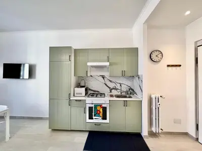 a kitchen with green cabinets and a clock on the wall at Casa Vacanze Jenner in Rome