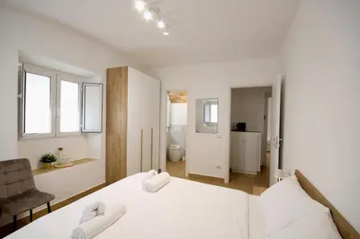 a white bedroom with a bed and a chair at HC - Pigneto Cozy & Modern Retreat in Rome