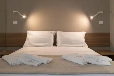 a bed with white sheets and pillows on it at Suemy Rome B&B in Rome