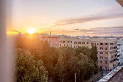 a sunset over a city with buildings and trees at San Giovanni Rooftop in Rome