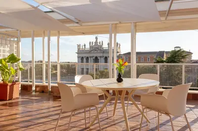 a balcony with a table and chairs and a building at San Giovanni Rooftop in Rome