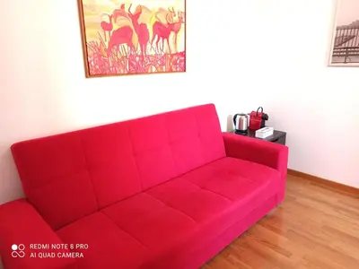 a red couch in a living room with a painting at Rome center near Colosseum and metro a in Rome