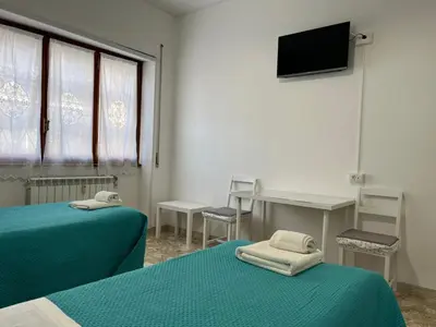 a room with two beds and a desk and a television at Alloggio Turistico Perez Martinez Maria Petronila in Rome