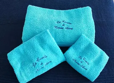 two blue towels with writing on them on a bed at La Casetta Di Nonna Anna - 120 mq Bright Apartment in Rome in Rome