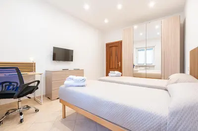 a bedroom with two beds and a desk and a television at Comfort House in Rome