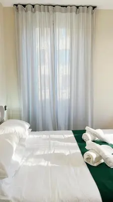 a bedroom with a bed with white sheets and a window at Laterano's House in Rome