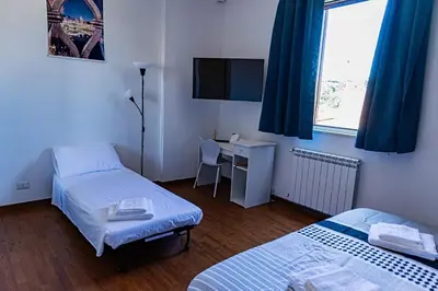 a room with two beds and a desk and a television at Terrace with view of Cupola San Pietro - Casa Claudia in Rome