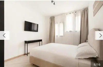 a white bedroom with a bed and a television at Trastevere City Life Apartments in Rome